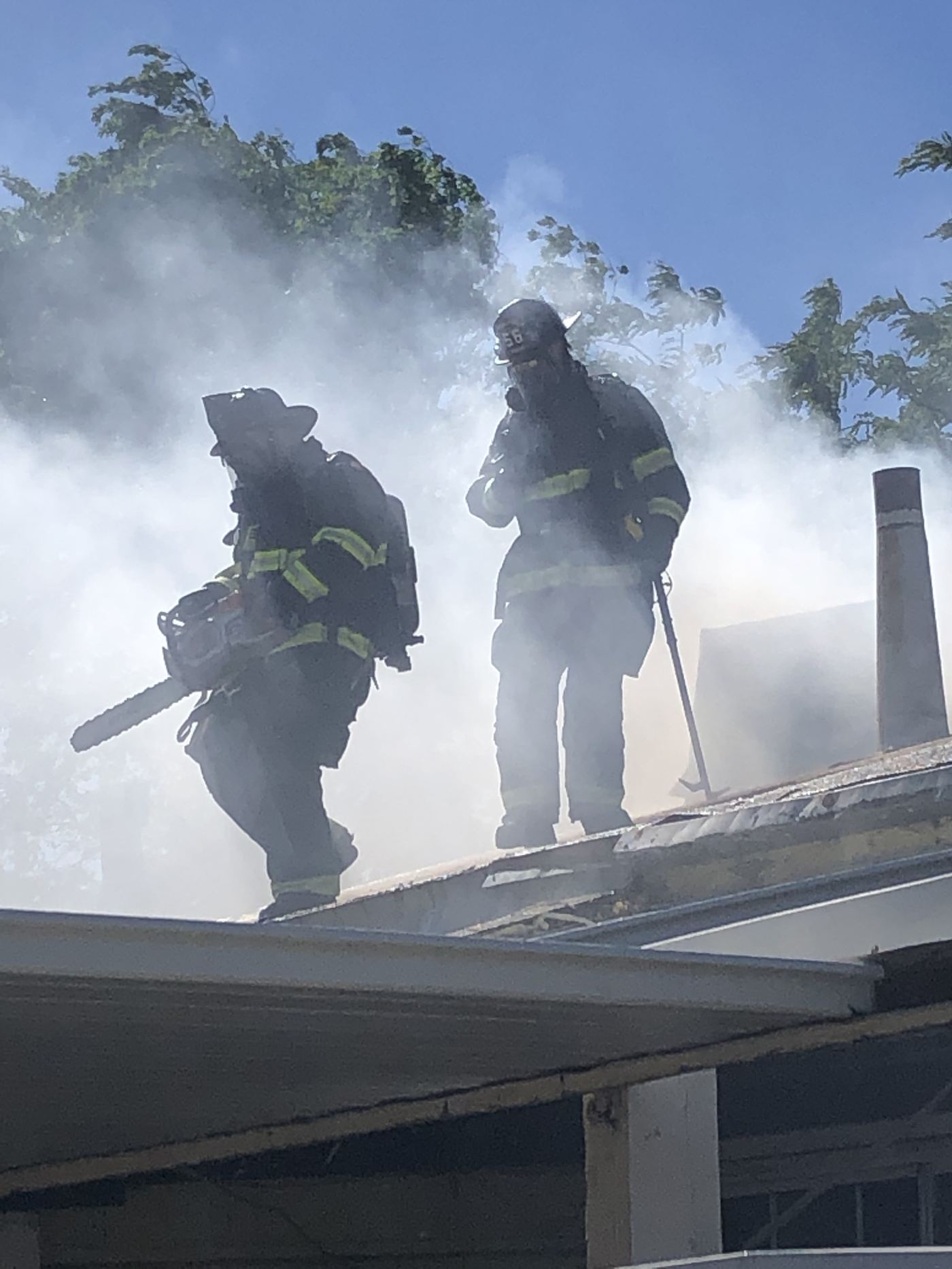 Two firefighters on a smoking rooftop during a fire